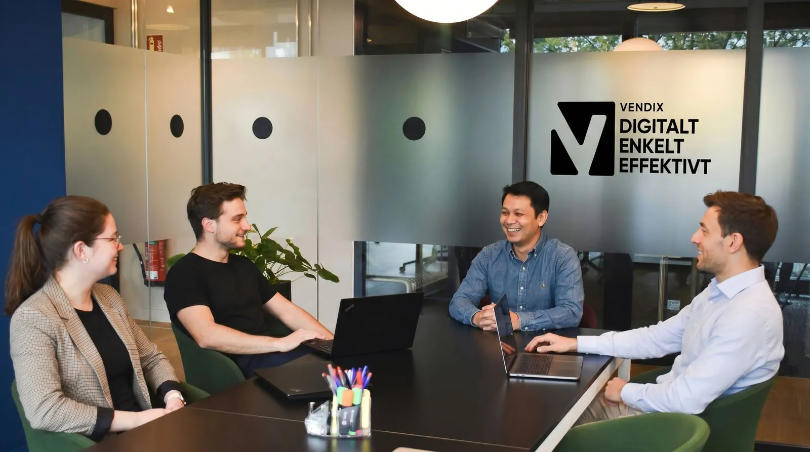 Vendix-teamet holder møde ved et mødebord foran Vendix-logoet på glasvæggen